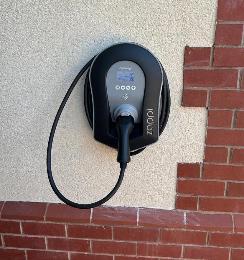 A sleek, modern EV charger installed on a brick wall of a home
